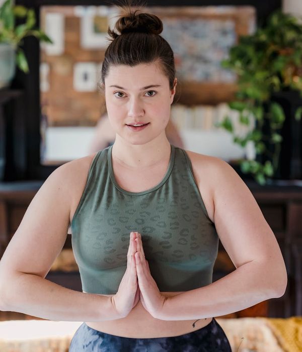 Woman in a calm yoga pose in a dark room with cyan light.